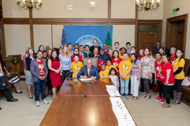 governor jay inslee sitting at a long table surrounded by children